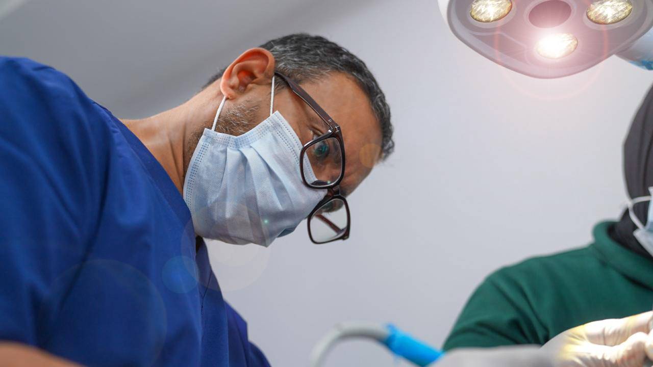 elite-smile-clinics-new-cairo-10 Dr. Ahmed Atteya performing procedure in operating room at Elite Smile Clinics New Cairo